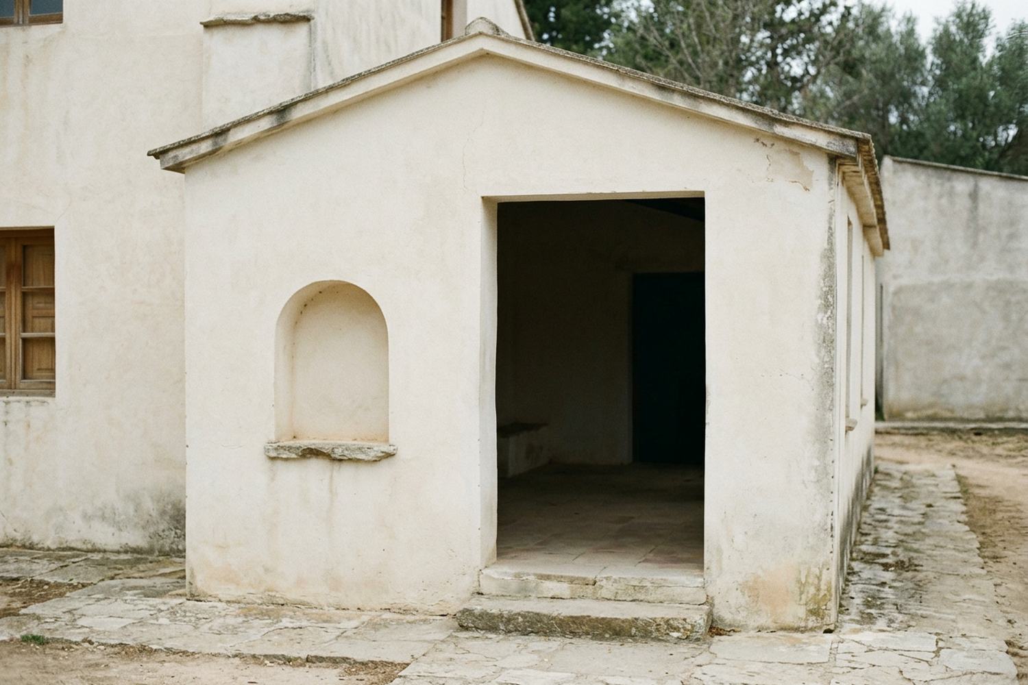 A deep covered entrance porch of plain masonry with a shallow step.